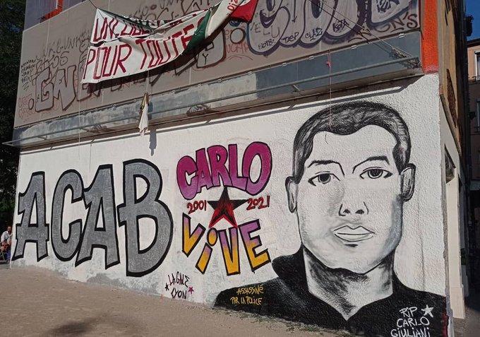 Street art on a wall in Lyon shows a portrait of Carlo Giuliani in black and white, with the accompanying text ACAB and CARLO VIVE