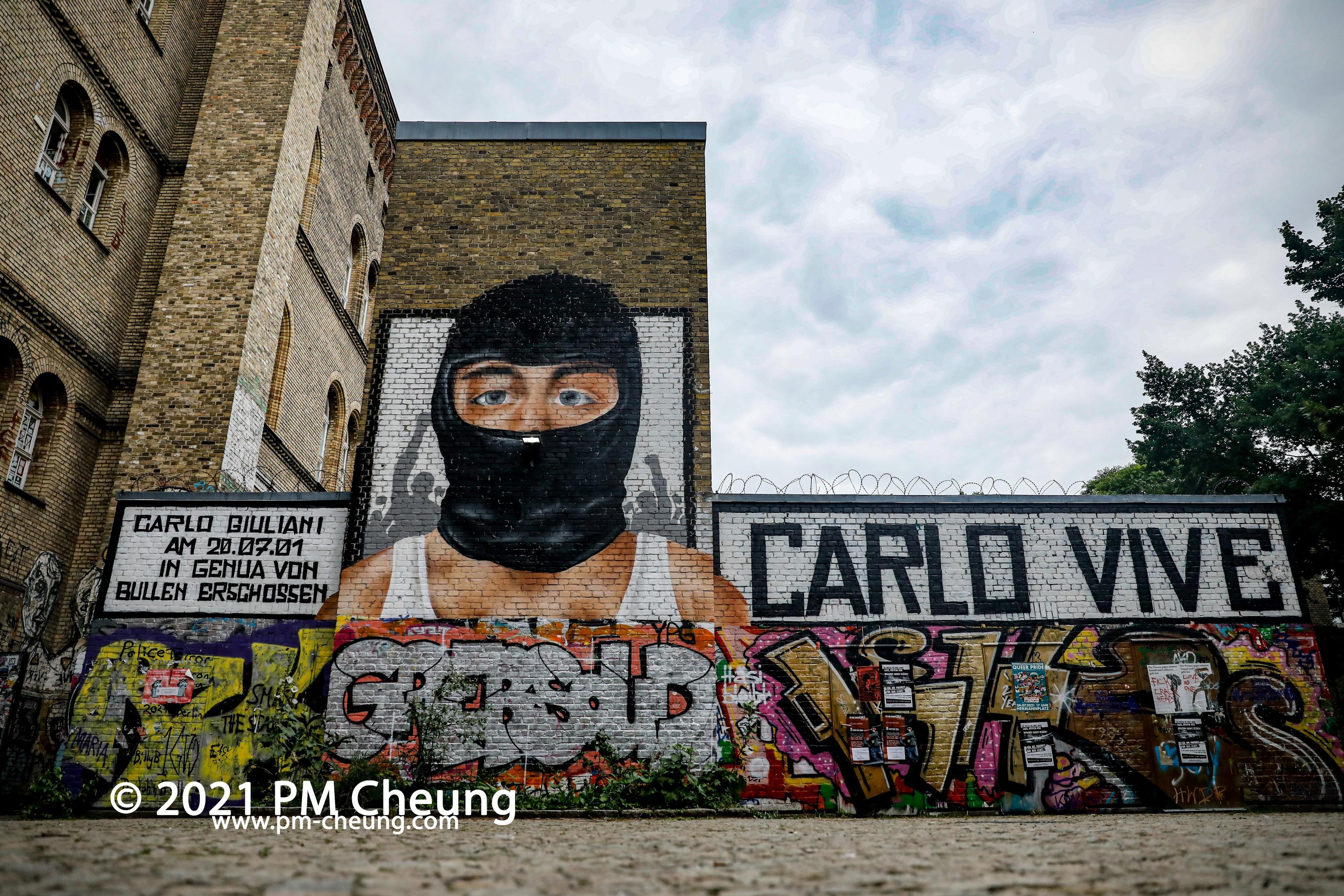 A wall in Berlin shows a colour portrait of Carlo with the words CARLO VIVE
